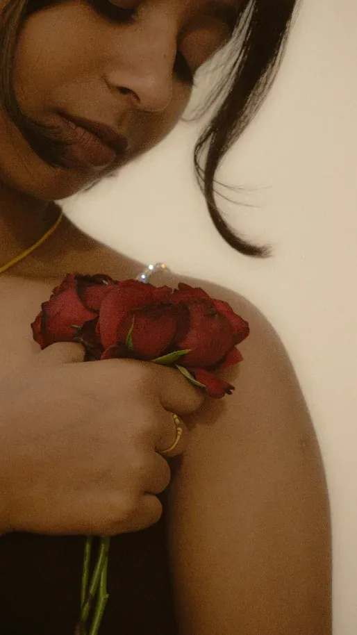 Mulher segurando rosas vermelhas junto ao ombro