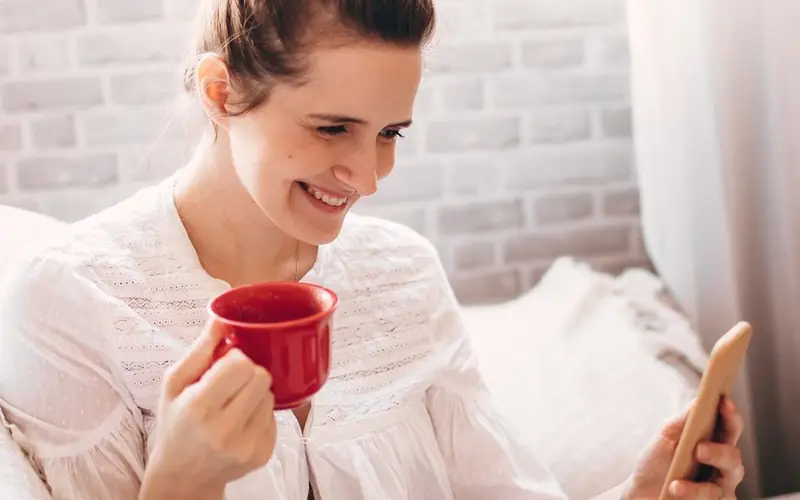 Mulher sorrindo enquanto usa o celular