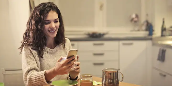 Mulher sorrindo enquanto escreve no celular